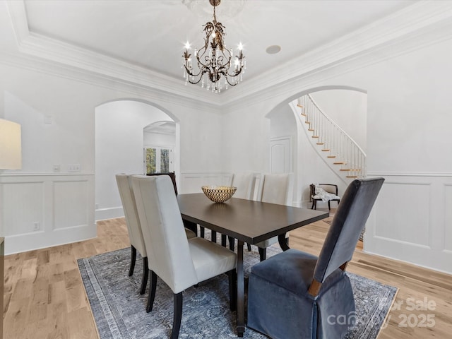 dining area featuring crown molding, a notable chandelier, and light hardwood / wood-style flooring