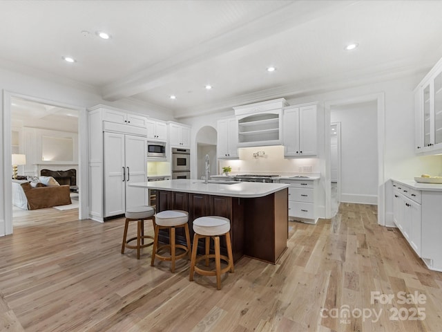 kitchen with a kitchen bar, sink, an island with sink, and white cabinets