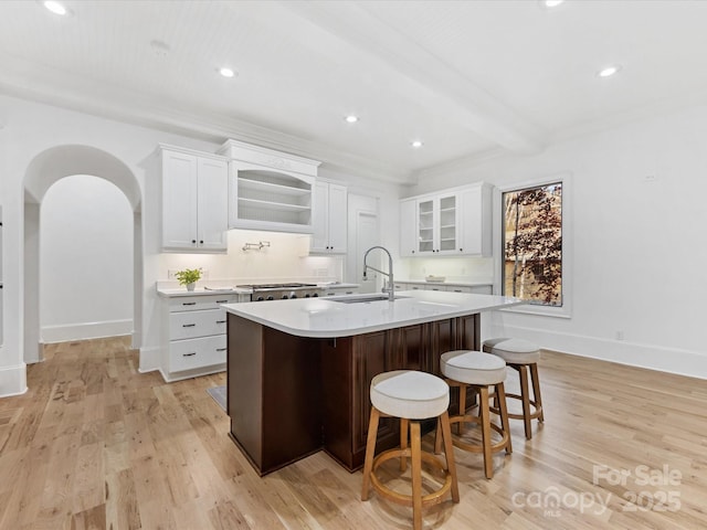 kitchen featuring sink, a breakfast bar area, white cabinetry, light hardwood / wood-style floors, and a center island with sink