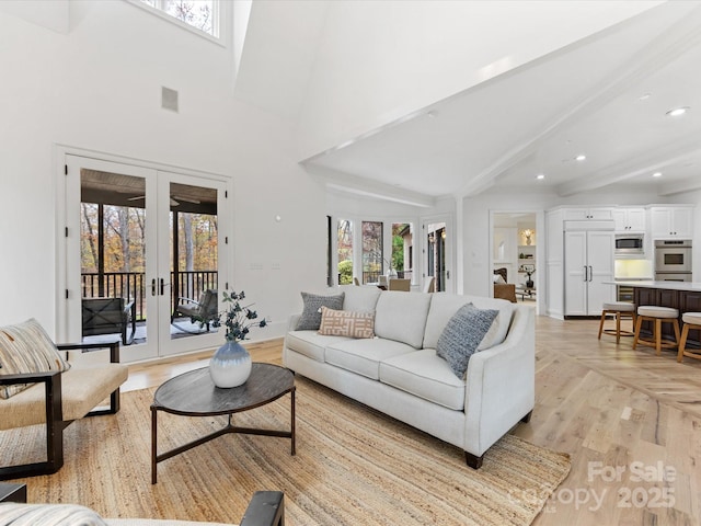 living room featuring beam ceiling, french doors, and a healthy amount of sunlight