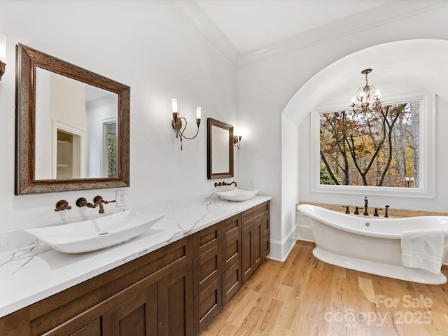 bathroom with a tub to relax in, crown molding, an inviting chandelier, vanity, and hardwood / wood-style flooring