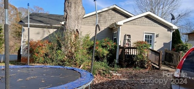 rear view of house with a deck and a trampoline