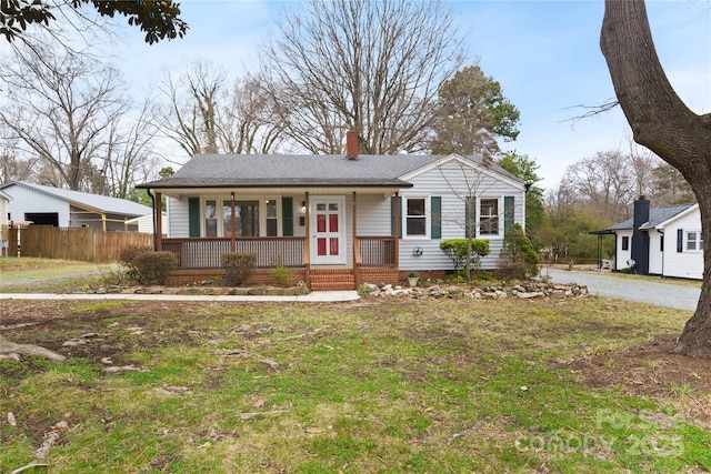 view of front of house featuring a chimney, roof with shingles, crawl space, fence, and a porch