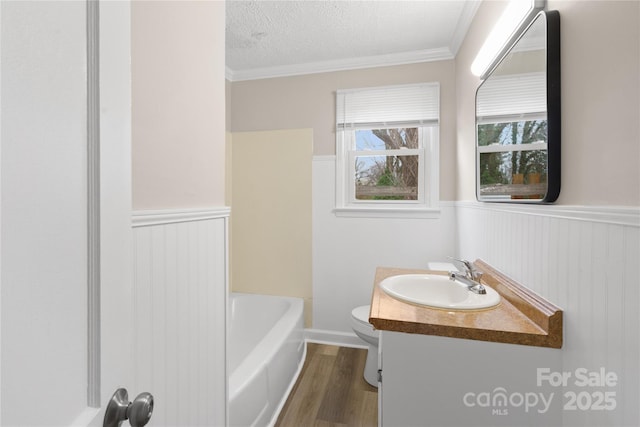 full bath with a textured ceiling, toilet, a wainscoted wall, wood finished floors, and vanity