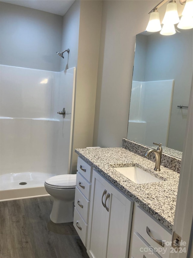 bathroom with a shower, vanity, hardwood / wood-style flooring, and toilet