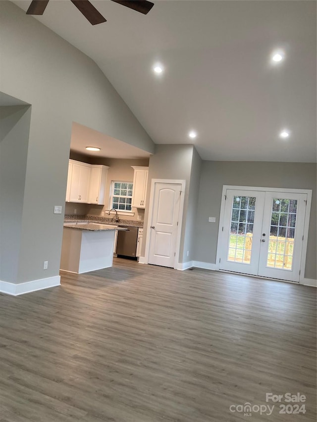 unfurnished living room featuring ceiling fan, french doors, sink, vaulted ceiling, and light wood-type flooring