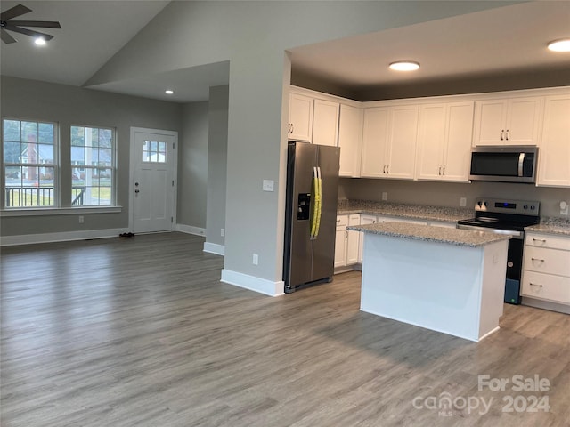 kitchen with appliances with stainless steel finishes, hardwood / wood-style flooring, white cabinetry, and lofted ceiling