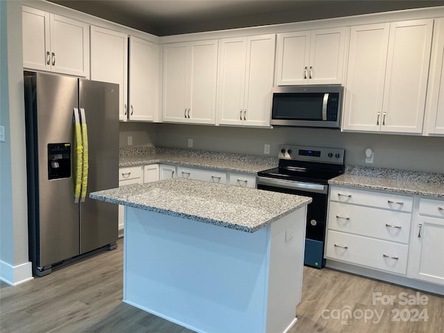 kitchen with white cabinets, appliances with stainless steel finishes, light hardwood / wood-style floors, and light stone counters