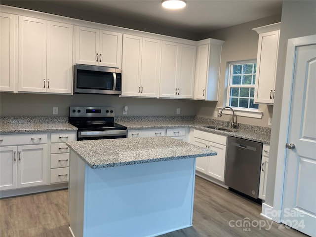 kitchen with appliances with stainless steel finishes, light hardwood / wood-style floors, white cabinetry, and sink