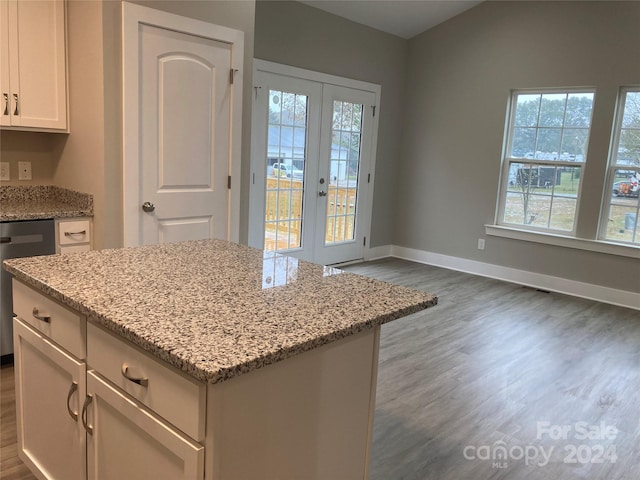 kitchen featuring dishwasher, french doors, light stone counters, a kitchen island, and dark hardwood / wood-style flooring