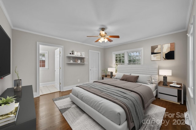 bedroom featuring dark hardwood / wood-style floors, ceiling fan, ensuite bathroom, and crown molding