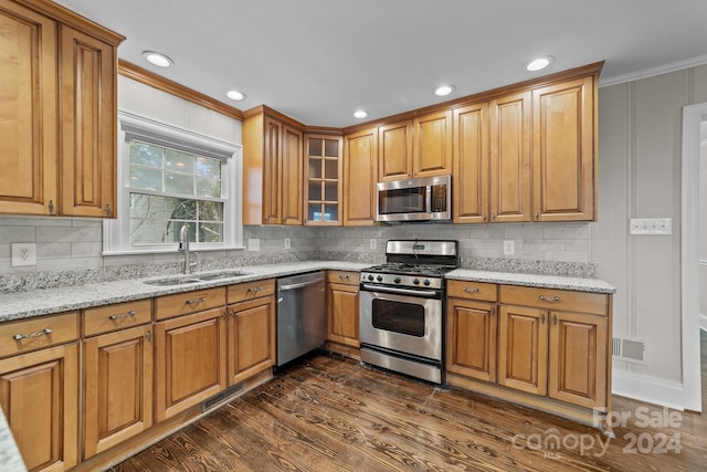 kitchen featuring sink, light stone counters, dark hardwood / wood-style flooring, crown molding, and appliances with stainless steel finishes