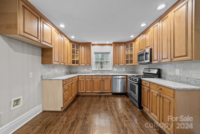 kitchen featuring sink, dark hardwood / wood-style floors, decorative backsplash, light stone countertops, and stainless steel appliances