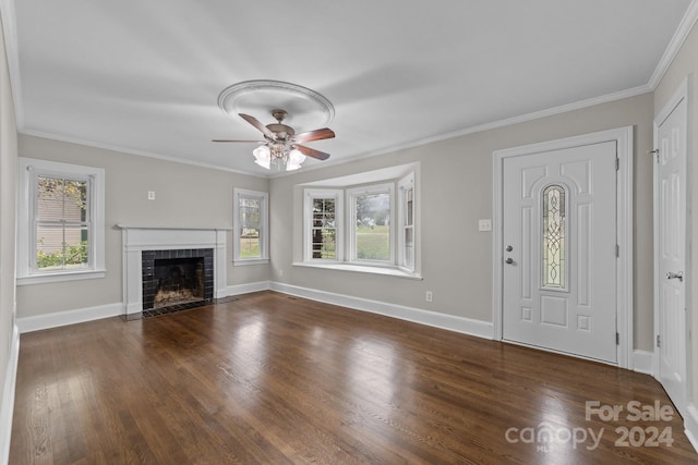 entryway with a tile fireplace, ceiling fan, dark wood-type flooring, and ornamental molding