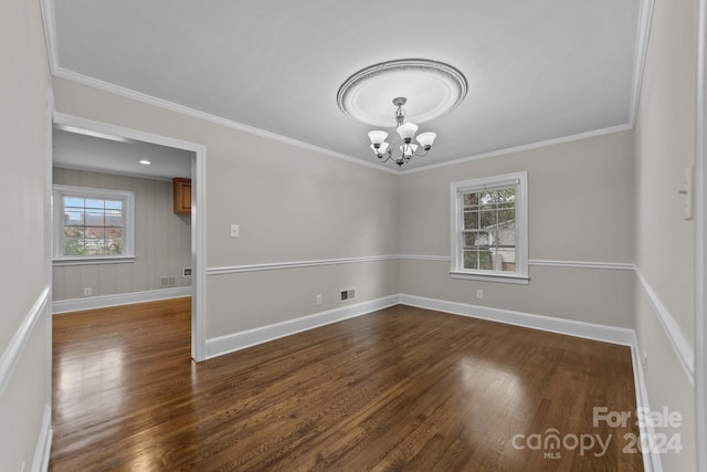 empty room with a notable chandelier, dark hardwood / wood-style flooring, and crown molding