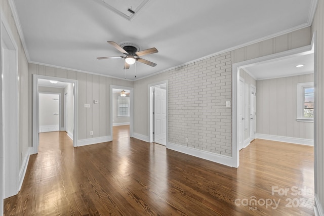 unfurnished room featuring hardwood / wood-style floors, ceiling fan, ornamental molding, and brick wall