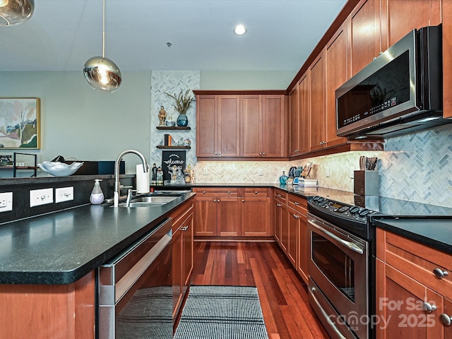 kitchen featuring dark hardwood / wood-style flooring, backsplash, stainless steel appliances, sink, and decorative light fixtures