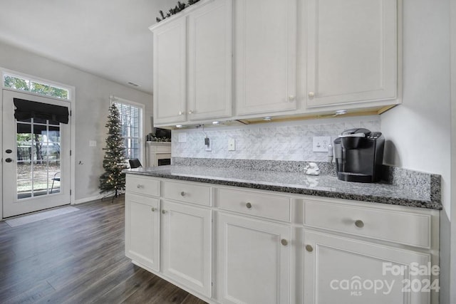 kitchen featuring dark hardwood / wood-style floors, dark stone countertops, white cabinetry, and decorative backsplash