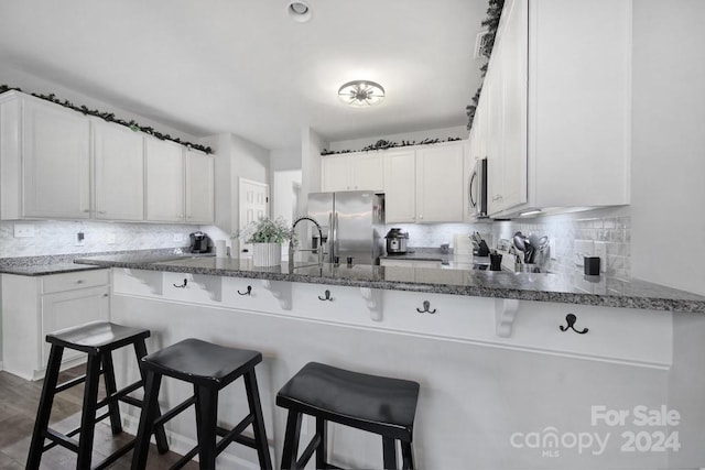 kitchen featuring a breakfast bar area, kitchen peninsula, white cabinets, and appliances with stainless steel finishes