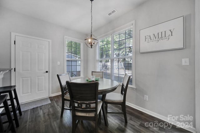 dining space with dark hardwood / wood-style floors and a notable chandelier