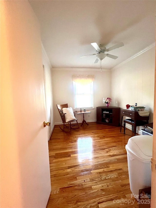 sitting room with hardwood / wood-style flooring, crown molding, and ceiling fan