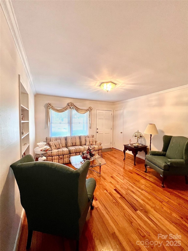 living room featuring built in shelves, ornamental molding, and light wood-type flooring