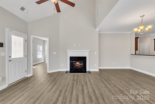 unfurnished living room with a glass covered fireplace, visible vents, baseboards, and wood finished floors