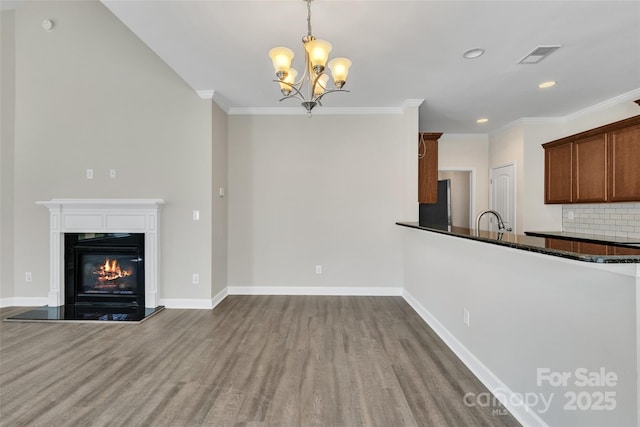 unfurnished living room featuring crown molding, baseboards, and wood finished floors