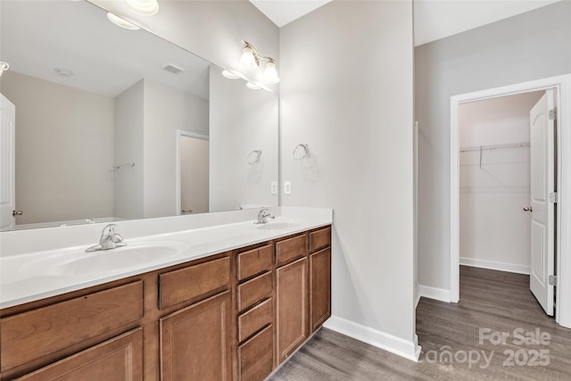 bathroom with double vanity, visible vents, a sink, and wood finished floors