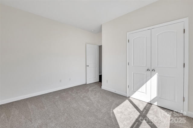 unfurnished bedroom with a closet, carpet, and baseboards