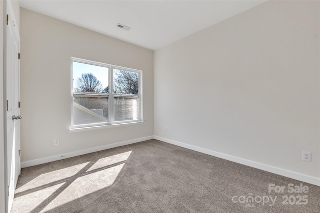 unfurnished room with carpet, visible vents, and baseboards