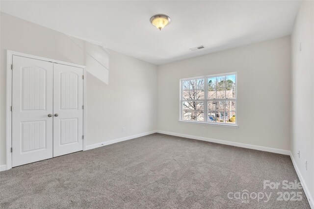 unfurnished bedroom with a closet, carpet, visible vents, and baseboards