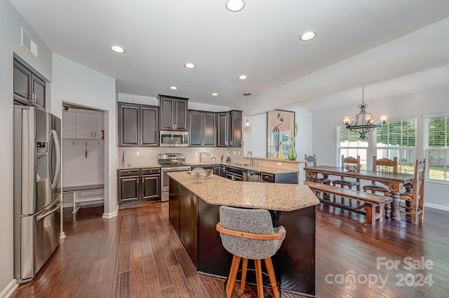 kitchen with stainless steel appliances, dark wood-type flooring, kitchen peninsula, hanging light fixtures, and a notable chandelier