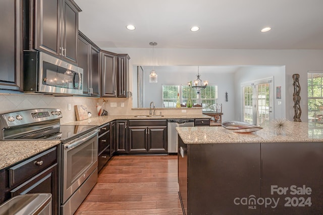 kitchen featuring stainless steel appliances, sink, decorative light fixtures, dark brown cabinets, and wood-type flooring