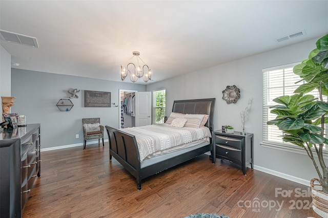 bedroom featuring dark hardwood / wood-style flooring, a chandelier, a closet, and a spacious closet