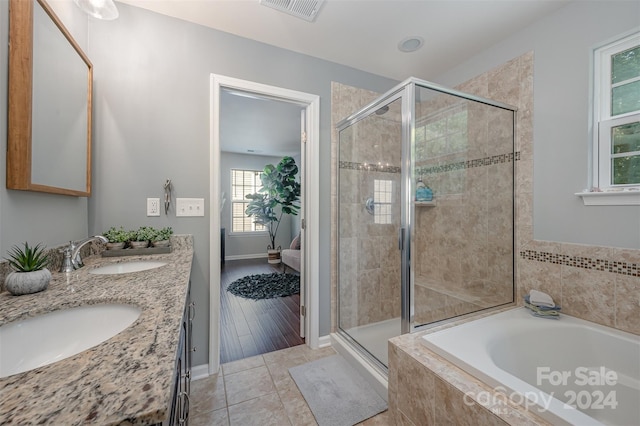 bathroom with wood-type flooring, vanity, and plus walk in shower