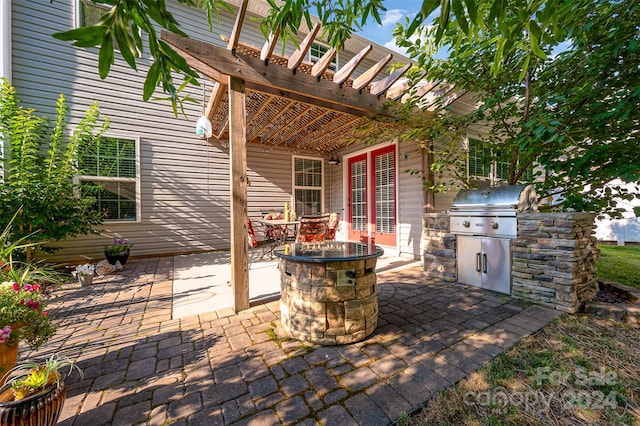 view of patio / terrace featuring grilling area, an outdoor fire pit, a pergola, and exterior kitchen