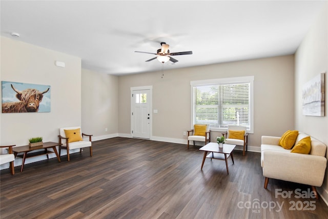 living area featuring dark wood finished floors, baseboards, and ceiling fan