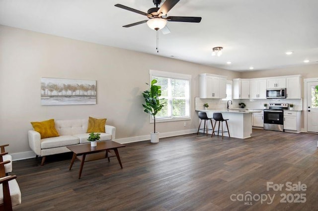 living room with dark wood-style floors, a healthy amount of sunlight, and baseboards