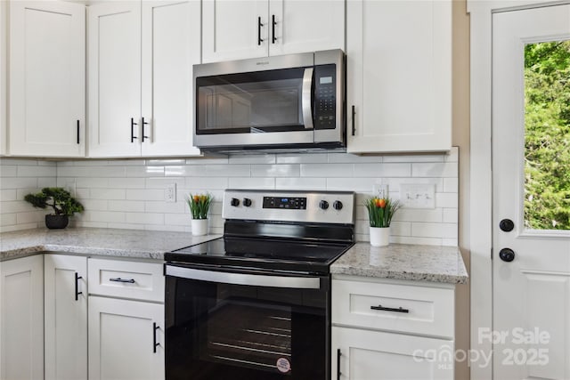 kitchen featuring white cabinets, backsplash, appliances with stainless steel finishes, and light stone counters