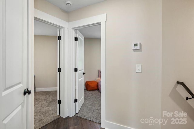 corridor with dark wood-style floors, baseboards, and dark carpet