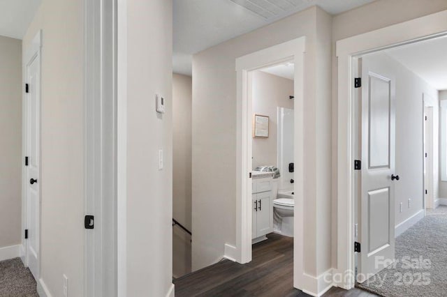 corridor with baseboards, an upstairs landing, visible vents, and dark wood finished floors