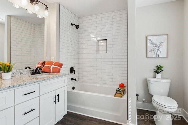 full bathroom with baseboards, toilet, vanity, wood finished floors, and washtub / shower combination