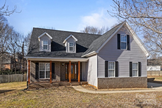 cape cod home featuring a front yard and a porch