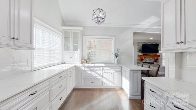 kitchen featuring light stone countertops, decorative light fixtures, white cabinetry, backsplash, and dark hardwood / wood-style floors