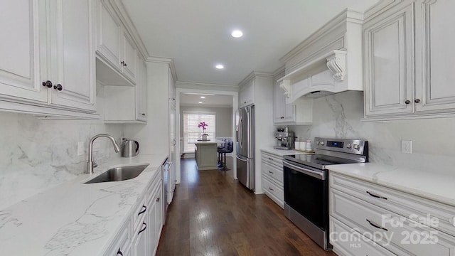 kitchen with light stone countertops, stainless steel appliances, white cabinetry, and sink