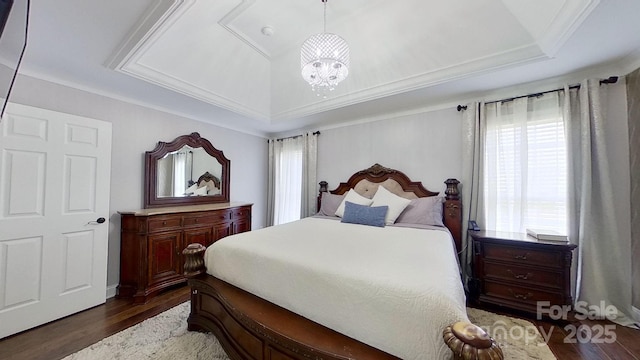 bedroom featuring dark wood-type flooring, multiple windows, a tray ceiling, and a chandelier