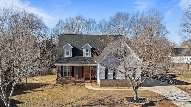 new england style home with covered porch and a front yard