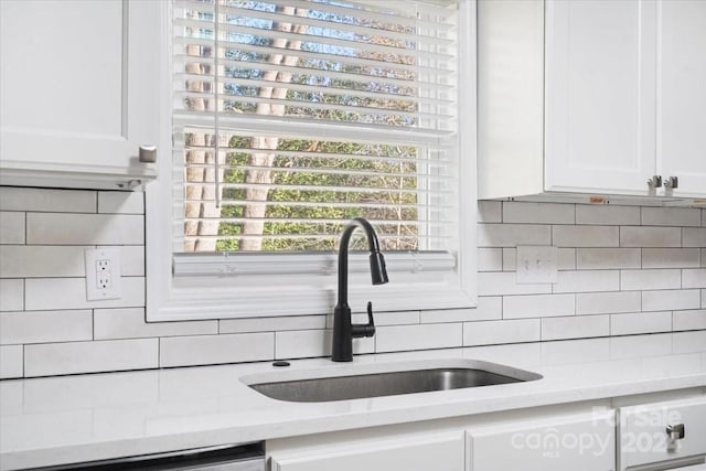 details featuring decorative backsplash, light stone counters, white cabinetry, and sink