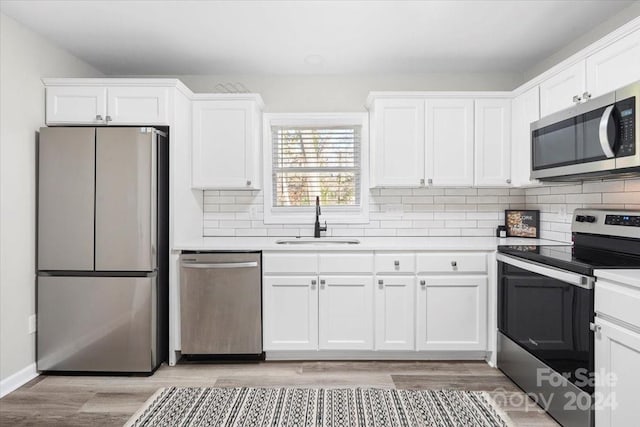 kitchen with light hardwood / wood-style flooring, stainless steel appliances, white cabinetry, and sink